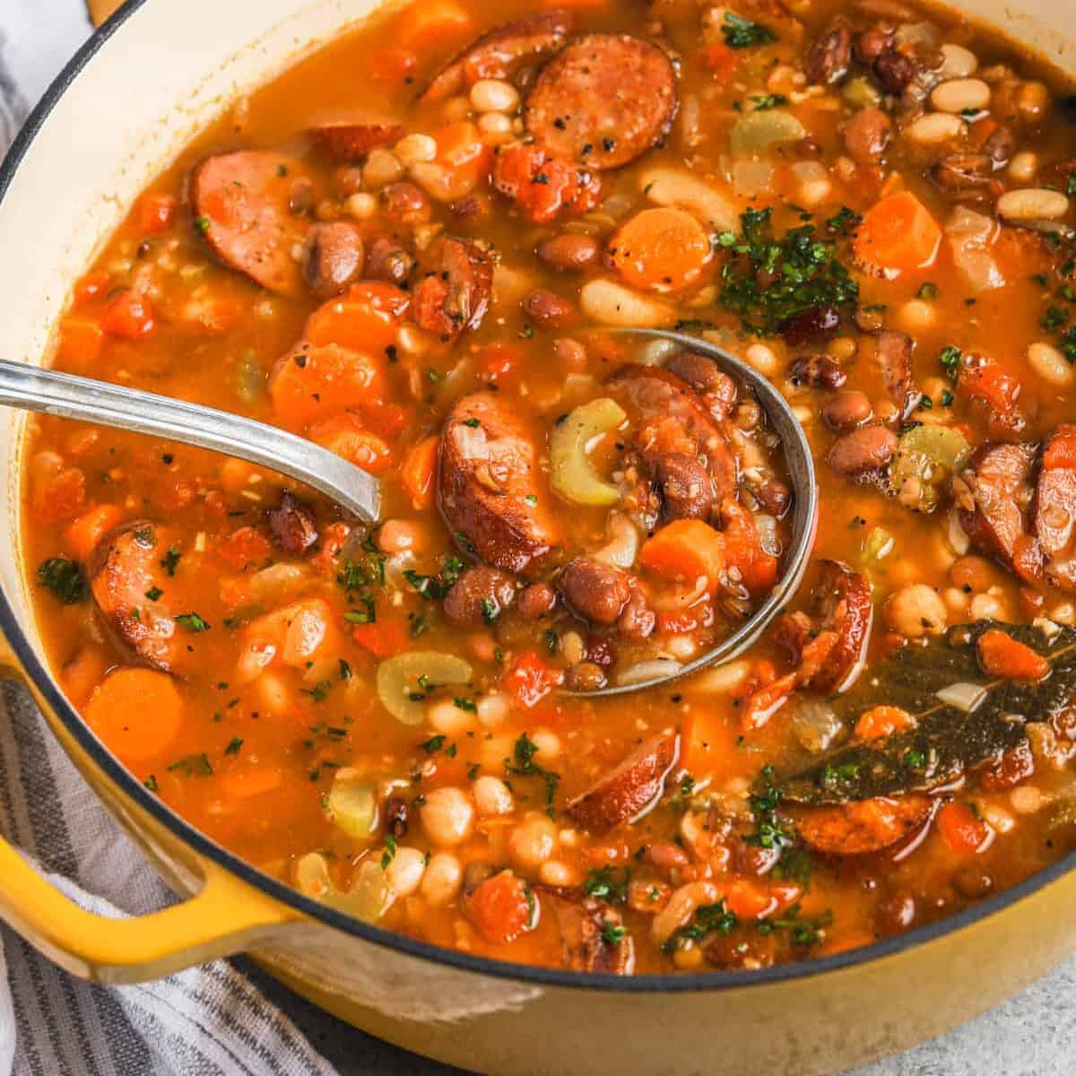 taking a spoonful of Bean Soup with Smoked Sausage out of the pot