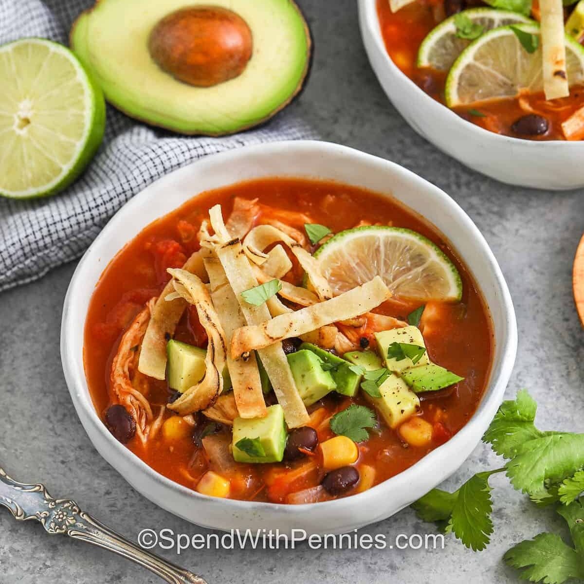 chicken tortilla soup in two bowls and an avocado
