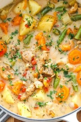 A cooked chicken and vegetable stew recipe in a white Dutch oven