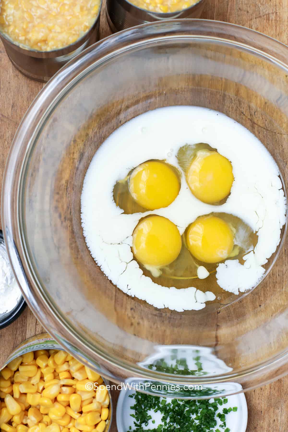This corn pudding recipe is a classic southern side dish that’s creamy, rich, and perfectly sweet. Made with creamed corn, whole kernels, butter, and a touch of brown sugar, every bite is smooth and flavorful. It’s an easy dish that fits right in with any family dinner or holiday feast. Serve it warm and watch it disappear fast at the table. This comforting favorite is a must-have side that always delights everyone. #spendwithpennies unwhipped eggs and milk in a bowl to make corn pudding