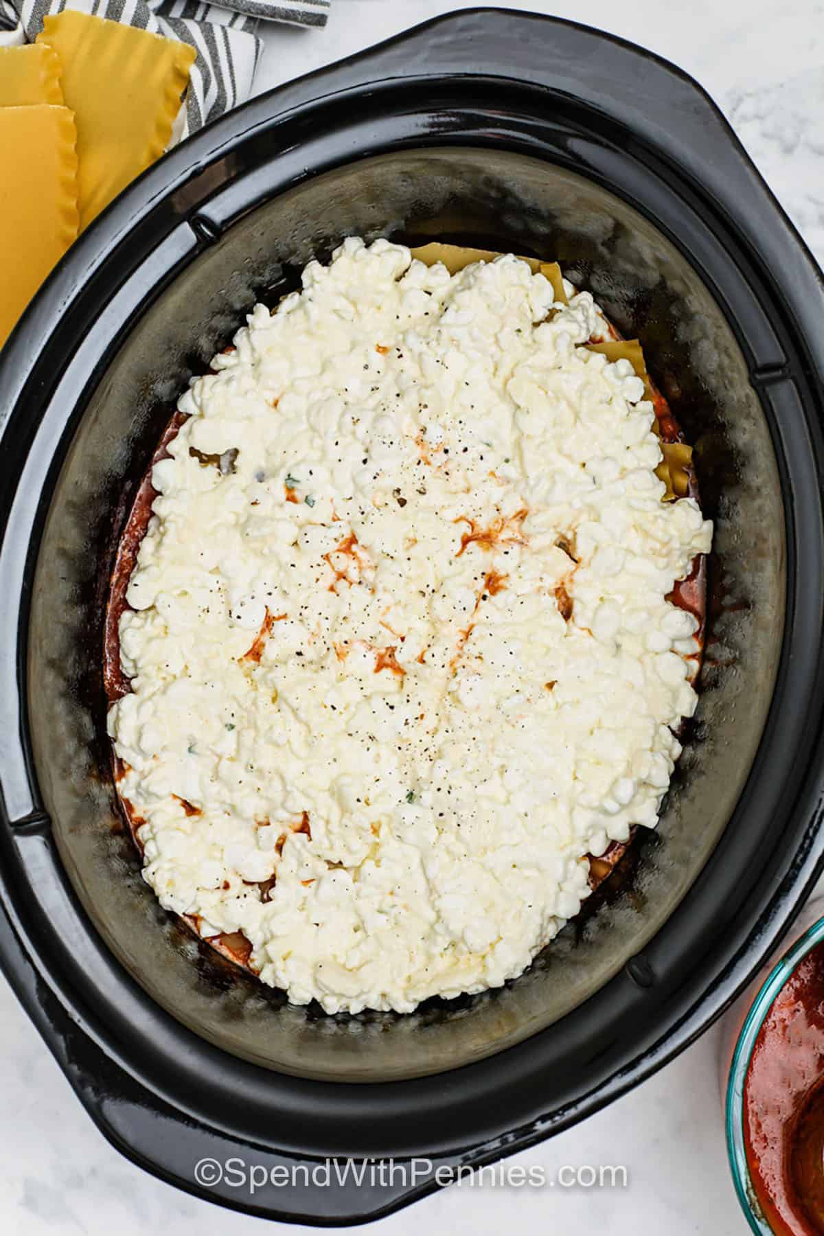 This crockpot lasagna recipe is rich, hearty, and full of Italian flavor. Layers of tender noodles, creamy ricotta, seasoned beef, and gooey cheese come together beautifully in the slow cooker. It’s a no-fuss way to make a homemade lasagna that turns out perfect every time. Serve it with a light veggie side or a green salad for a complete dinner. #spendwithpennies adding seasonings to Crockpot Lasagna before cooking