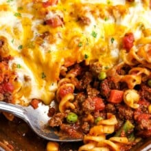 Hamburger casserole being scooped out of the casserole dish with a spoon