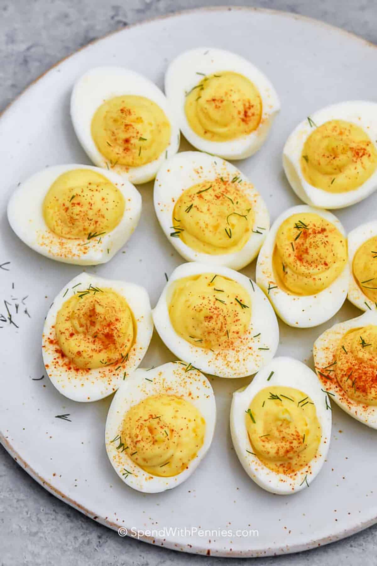 For a tangy deviled eggs recipe that everyone will love, this version is easy and flavorful. The yolks are blended with mayonnaise, mustard, and vinegar, then finished with paprika or crumbled bacon. It makes a beautiful and tasty appetizer for any gathering. Serve alongside fresh vegetables or a cheese platter to elevate the presentation. #spendwithpennies creamy Deviled Eggs on a plate