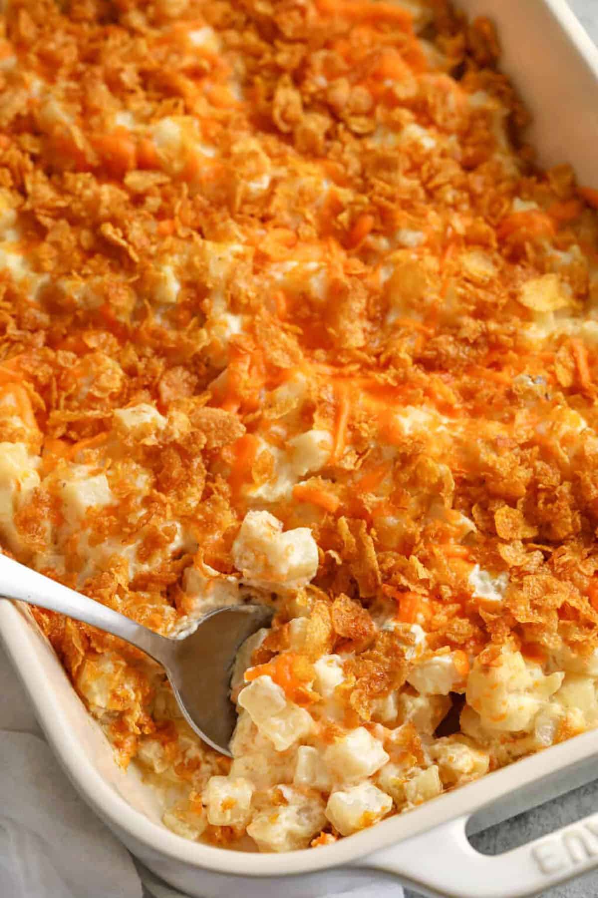 If you’re looking for the best comfort dish to show someone you care, this funeral potatoes recipe checks every box. Made with frozen hash browns, cream, and cheese, it bakes into a rich, bubbling casserole. You can easily make it in a crock pot when you need to keep things simple. The crispy topping adds just the right crunch. This creamy, cheesy side is a favorite for potlucks and family dinners alike. #spendwithpennies dish of Funeral Potatoes with a spoon