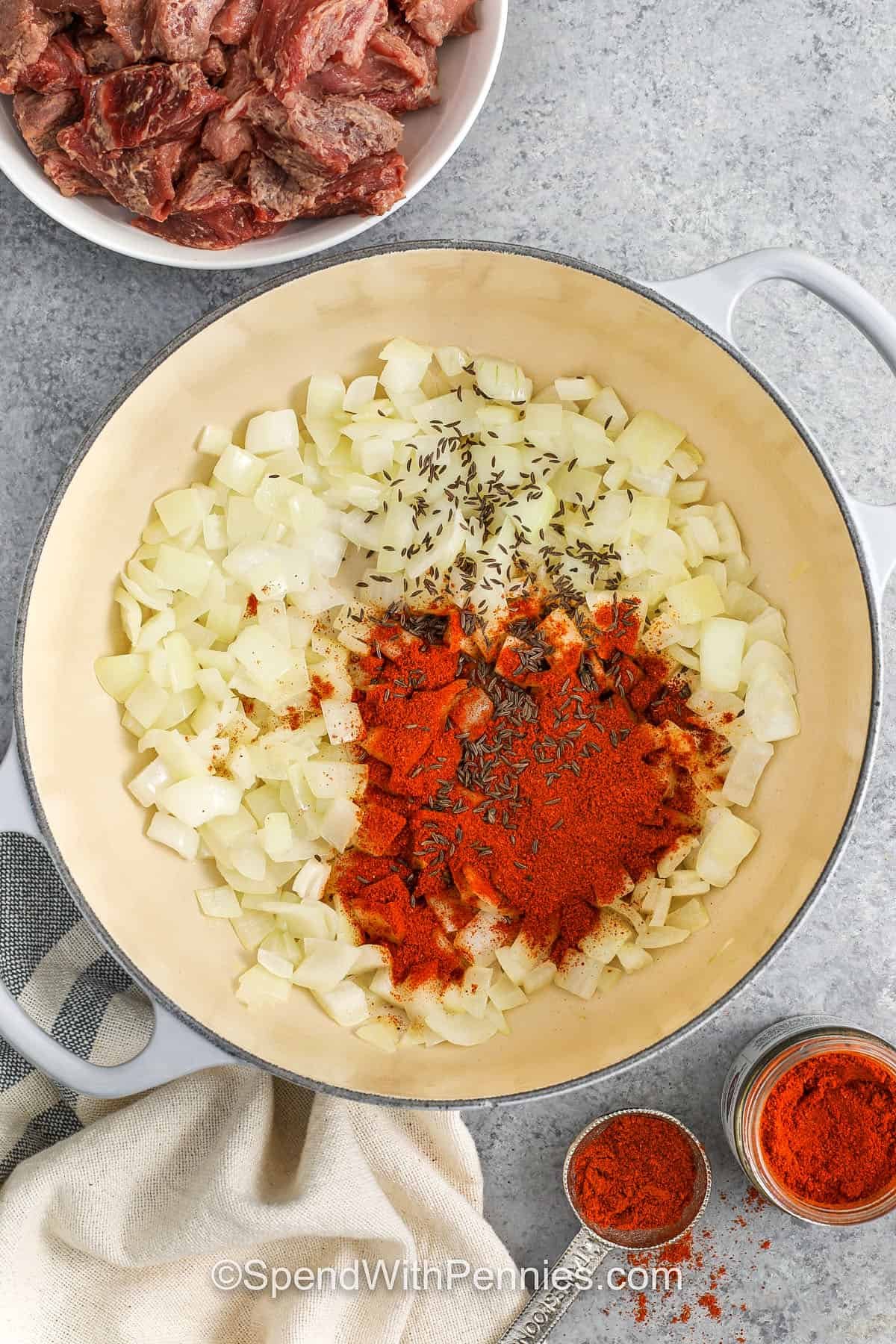 Hungarian goulash is a classic beef recipe that’s both hearty and delicious. It features chunks of beef simmered in a tomato and paprika broth that’s rich, flavorful, and so comforting. Add carrots and potatoes for a full meal in one pot, and serve with bread or noodles to soak up every drop. Simple, warming, and perfect for family dinners. #spendwithpennies adding seasonings to onions with caraway seeds to make Hungarian Goulash