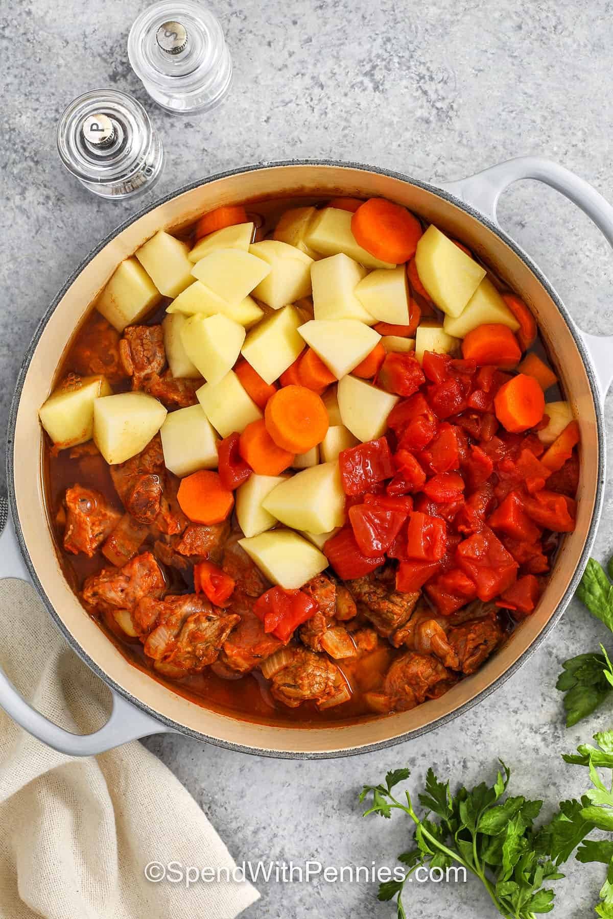 Hungarian goulash is the best beef stew to cozy up with on a cool night. Tender beef, onions, and paprika come together in a rich tomato-based broth for bold, comforting flavor. Add carrots and potatoes to make it even heartier, and finish with a dollop of sour cream. Whether made on the stovetop or slow cooked in the oven, it’s always satisfying. #spendwithpennies adding potatoes , carrots and tomatoes to pot to make Hungarian Goulash