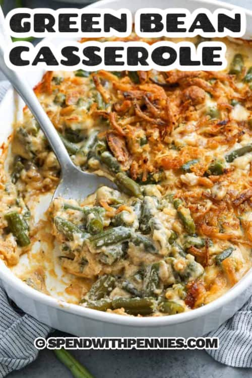 In this green bean casserole, mushroom soup, tender green beans, and crispy fried onions come together in one perfect bite. It’s quick to prepare, can be made ahead of time, and goes straight from oven to table. Whether it’s Thanksgiving or a weeknight dinner, this classic dish brings cozy, nostalgic flavor everyone loves. #spendwithpennies delicious Green Bean Casserole in a casserole dish with a spoon with a title