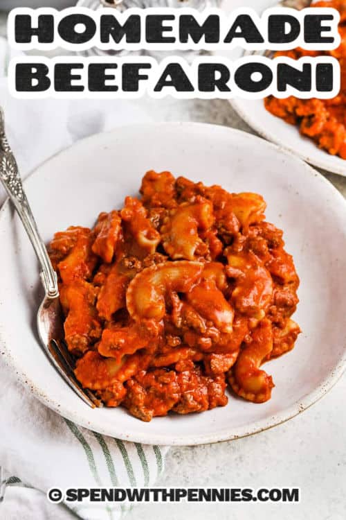 Homemade beefaroni made with tender pasta, savory ground beef, and rich tomato sauce is the ultimate comfort food. Cream cheese adds a hint of tangy creaminess, while cheddar brings a cheesy finish. This one-pot recipe comes together easily and is perfect for busy weeknights or cozy family dinners. Hearty, filling, and full of flavor, it’s a dish everyone will love coming home to. #spendwithpennies beefaroni on a white bowl with writing