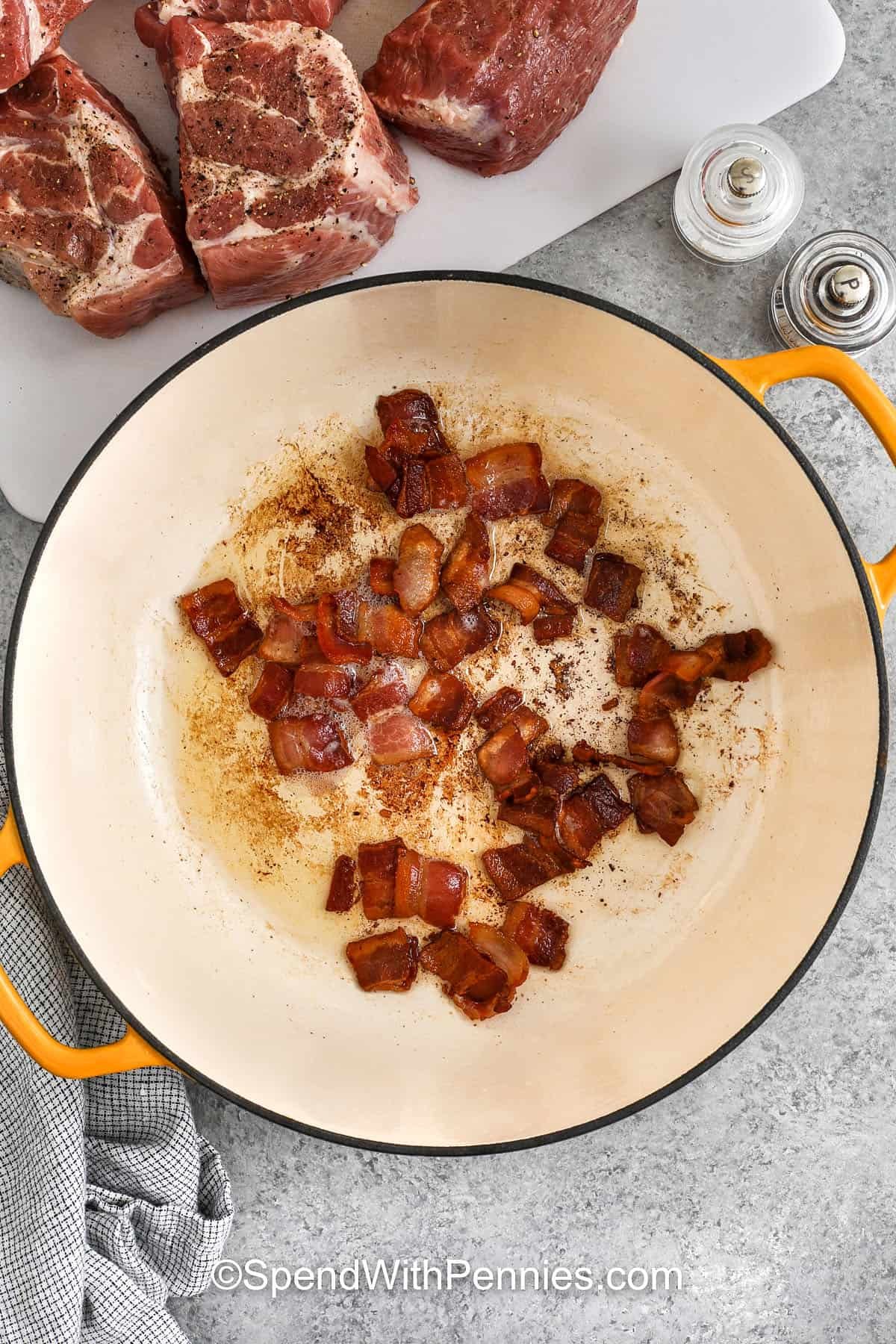 Pork and beans is a deliciously comforting dish made with tender pork and baked beans simmered in a rich sauce that’s sweet, tangy, and full of flavor. The smoky bacon, onion, and garlic blend beautifully with a savory broth seasoned with mustard and vinegar. This simple and satisfying meal is perfect for family dinners, cozy weekends, or potluck gatherings. #spendwithpennies cooking bacon to make Pork and Beans