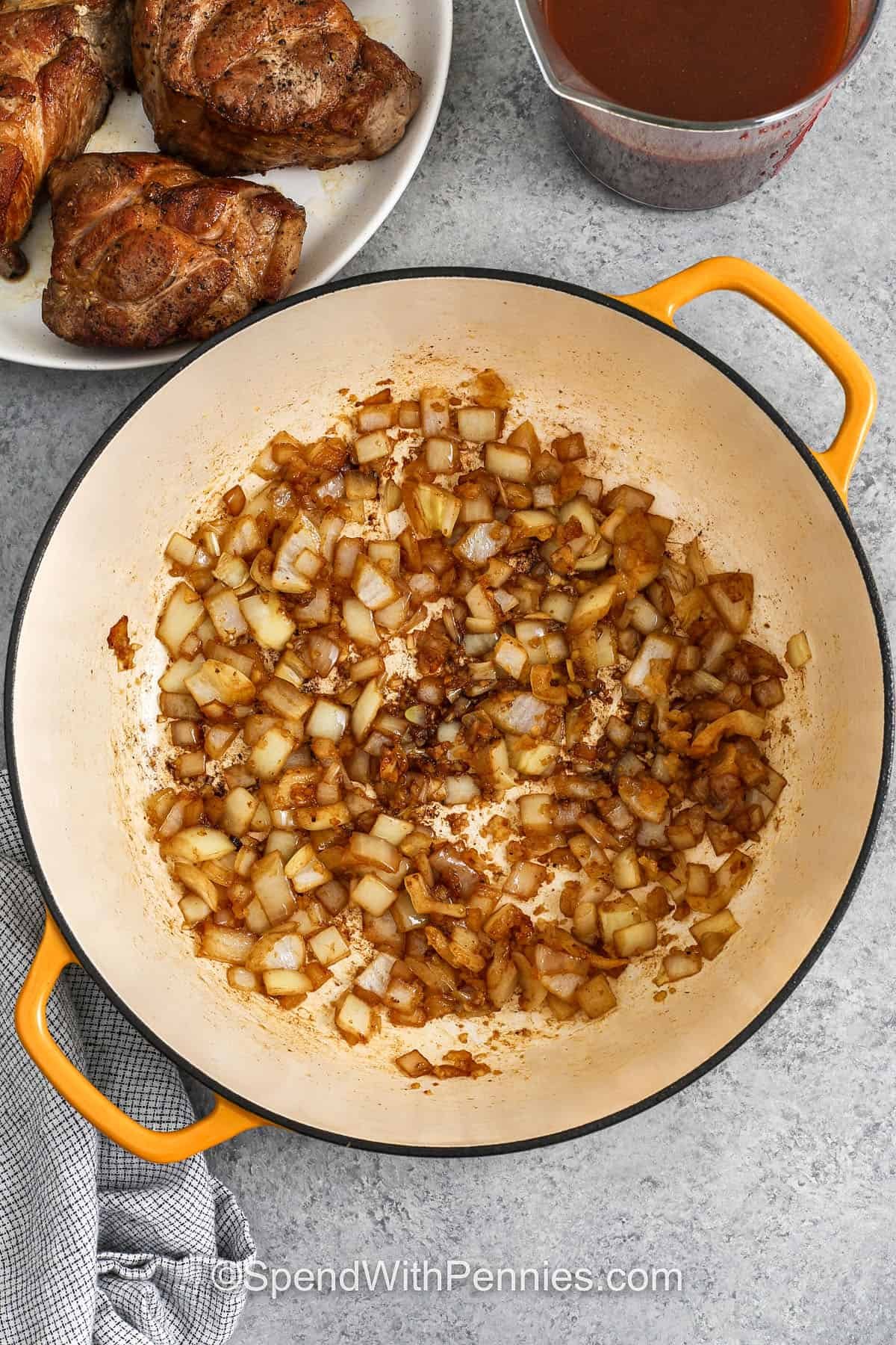 Pork and beans is a cozy, flavorful dish made with tender pieces of pork, baked beans, and a sauce that’s the perfect balance of sweet and tangy. Smoky bacon, onion, garlic, and a seasoned broth with mustard and vinegar bring rich, homemade flavor to every bite. Great for weeknight dinners, potlucks, or relaxed weekends, this easy recipe is warm, hearty, and always satisfying comfort food. #spendwithpennies cooked onions in pot to make Pork and Beans