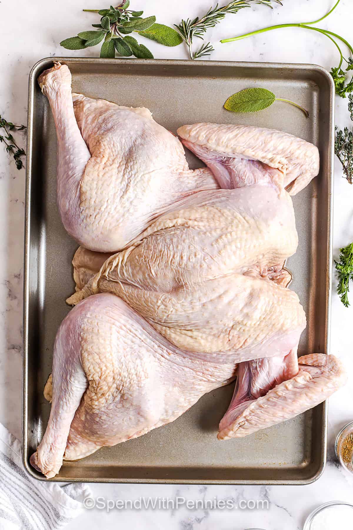 Spatchcock turkey is the best way to get juicy meat and crisp, flavorful skin every time. Flattening the bird helps it roast evenly and keeps the flavor locked inside. Rub it with olive oil, herbs, and seasoning for a beautiful golden finish. This easy recipe works well for a 10 to 12 lb bird and makes enough to feed a crowd. Serve with classic sides for a holiday meal everyone will remember. #spendwithpennies turkey on sheet pan before adding seasonings