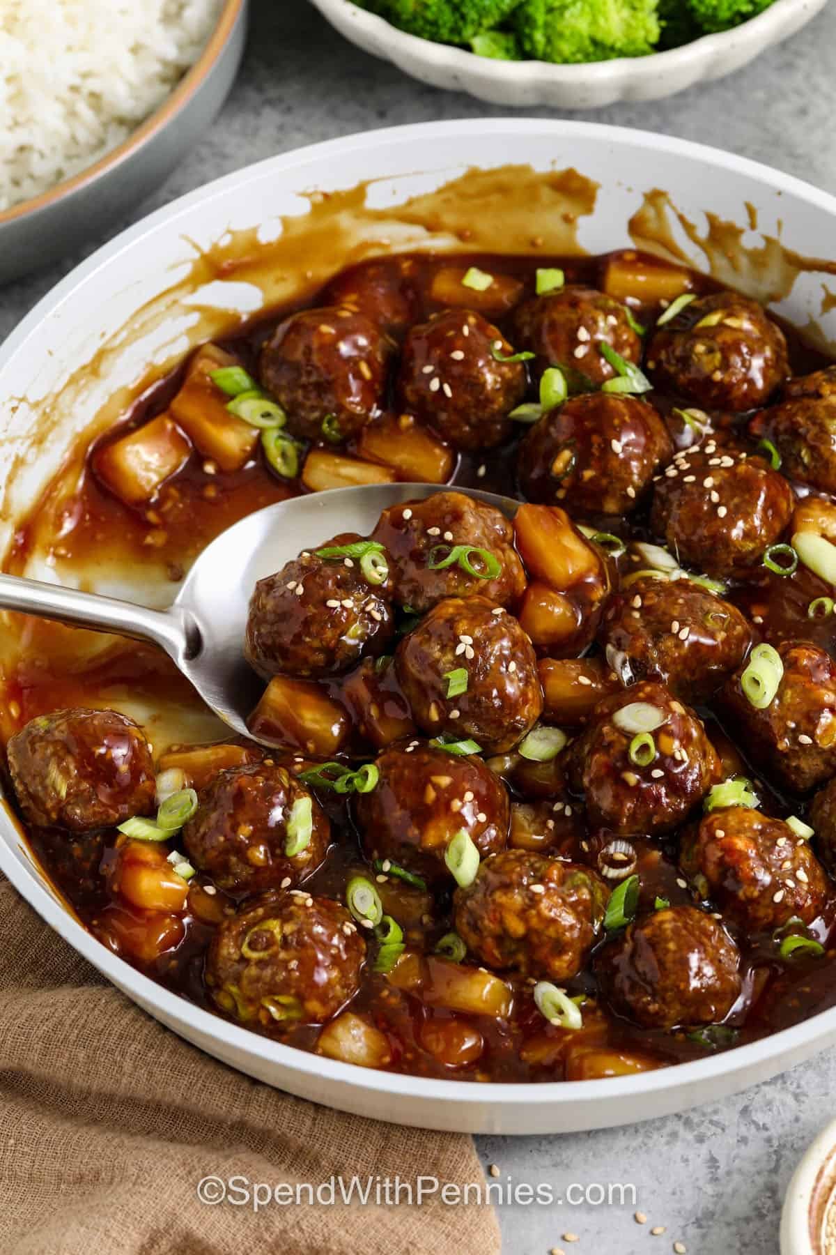 serving terkiyaki meatballs from the pan, with spoon