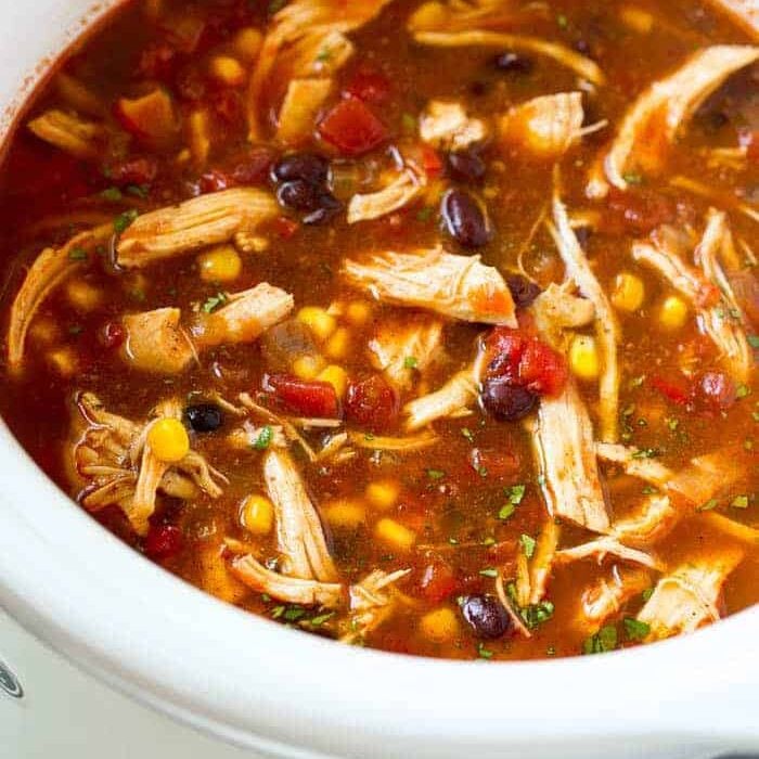 A slow cooker filled with shredded chicken and vegetables