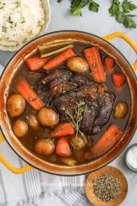 a cooked pot roast recipe in a Dutch oven with carrots and potatoes