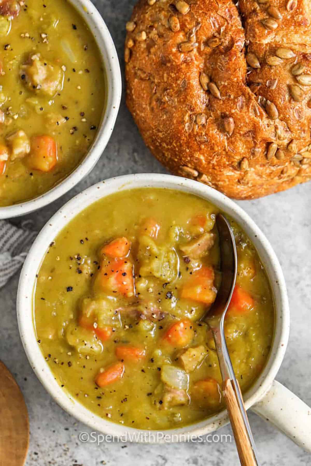 Split pea soup is the ultimate comfort food for chilly days, made thick, creamy, and naturally rich without any cream. This old-fashioned recipe uses simple pantry staples like split peas, carrots, celery, and smoky leftover ham to create a hearty one-pot meal. It’s perfect for meal prep, freezer-friendly, and reheats beautifully for cozy family dinners or quick lunches. #spendwithpennies Split Pea Soup in bowls with a spoon