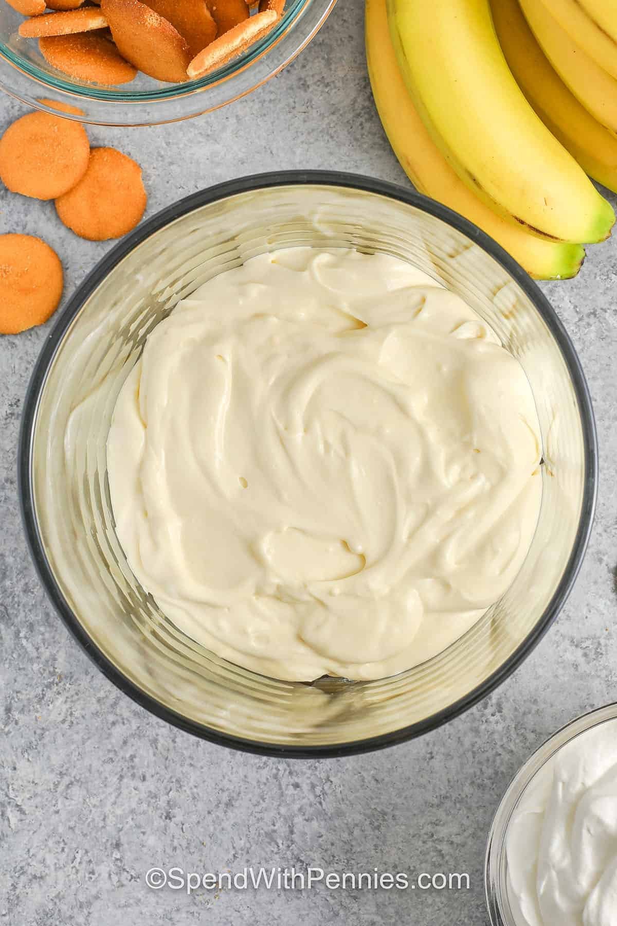 This banana pudding recipe brings together layers of creamy vanilla pudding, whipped cream, and fresh bananas for the best dessert. Sweet milk and soft cream cheese blend for a smooth, rich flavor, while Nilla wafers give it a subtle crunch. It’s like a mix between pie and cake, and everyone loves how easy it is to make. Each layer soaks up the sweet pudding for that perfectly soft texture. #spendwithpennies adding pudding layer to dish to make Banana Pudding