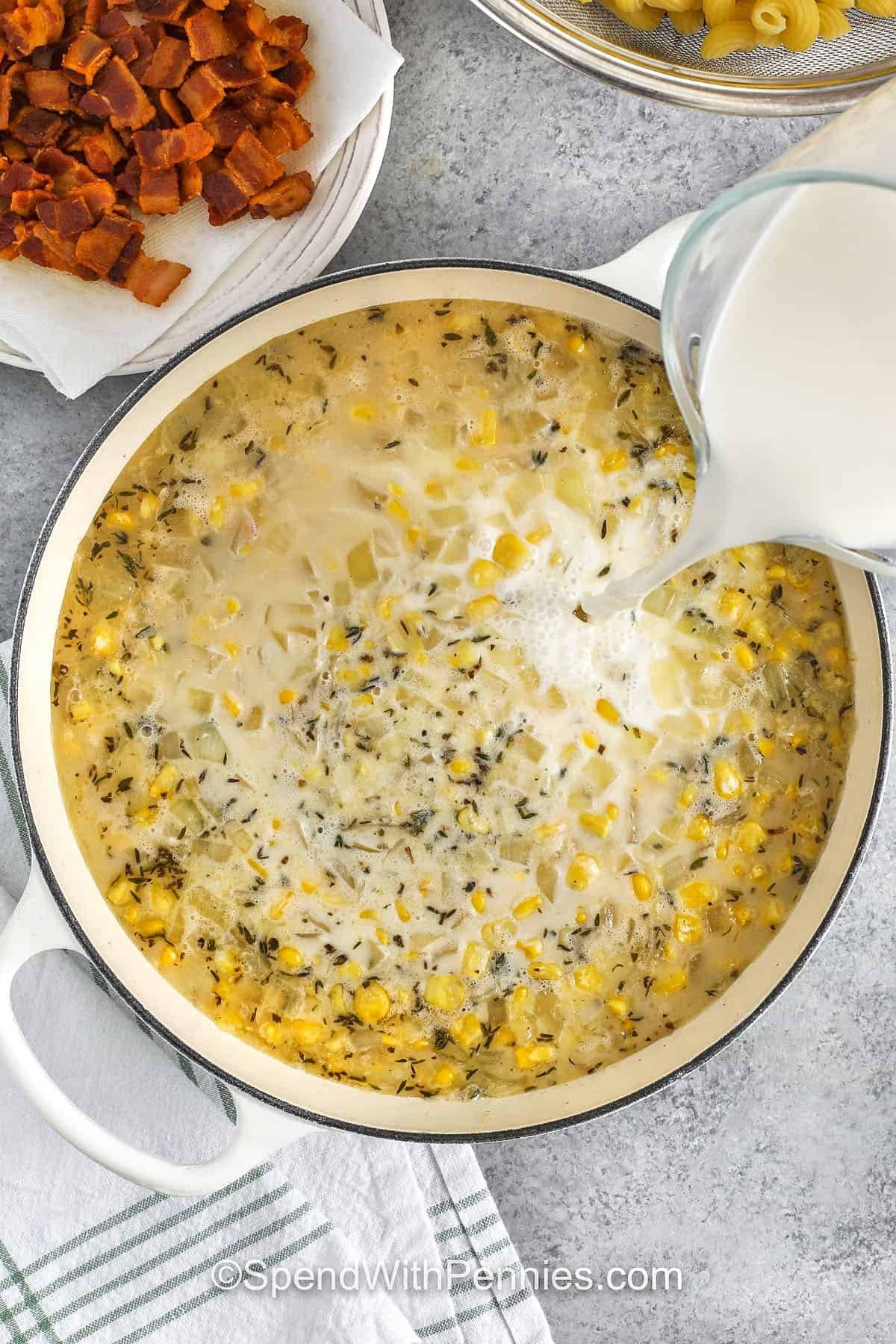 pouring the cream into corn pasta in a pot