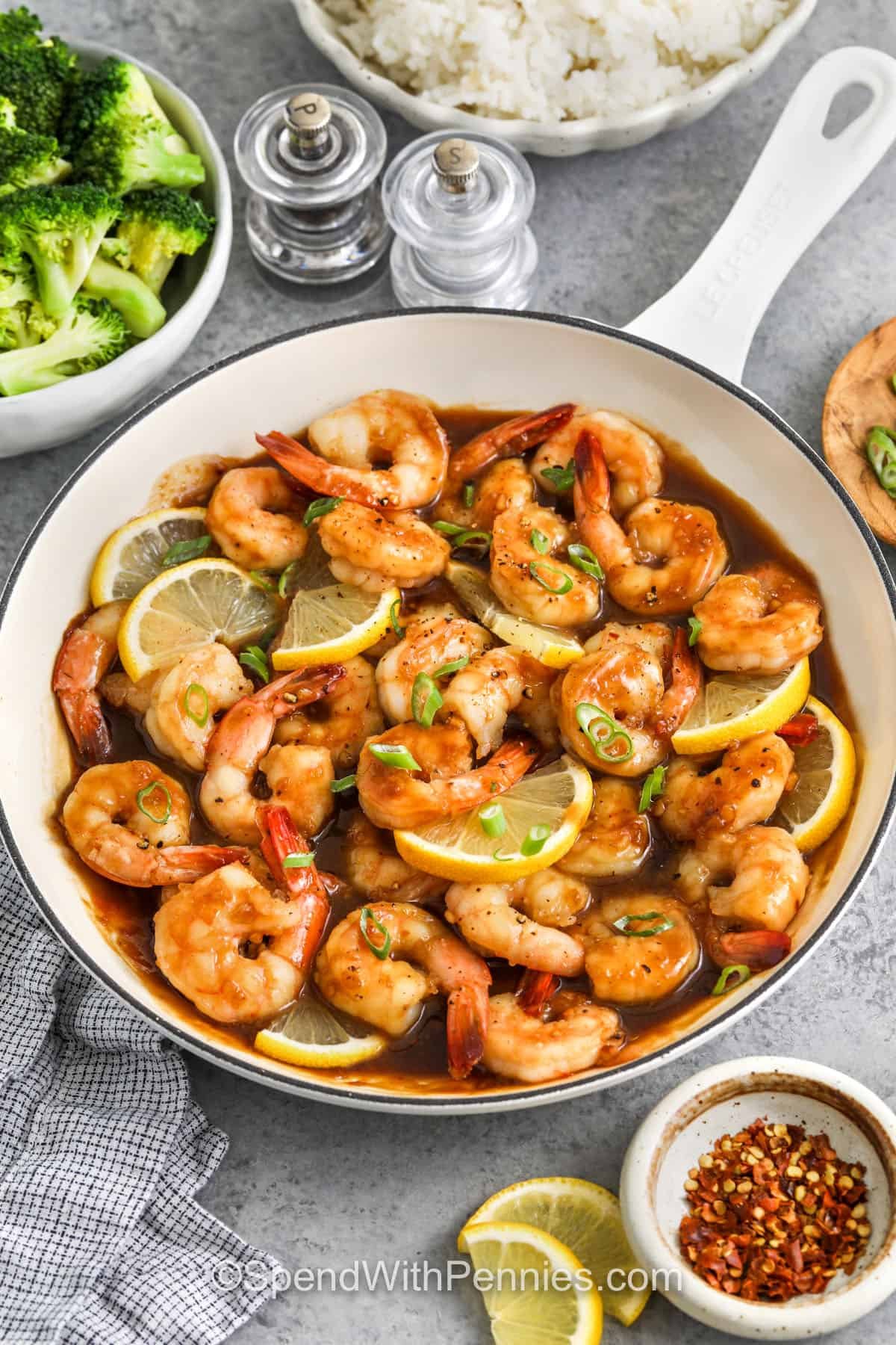 a pan of honey garlic shrimp with lemon wedges