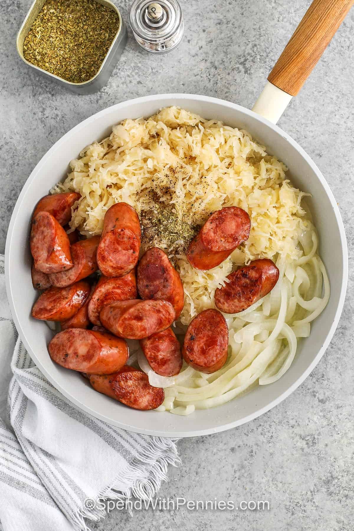 adding ingredients together in pan to make Kielbasa and Sauerkraut