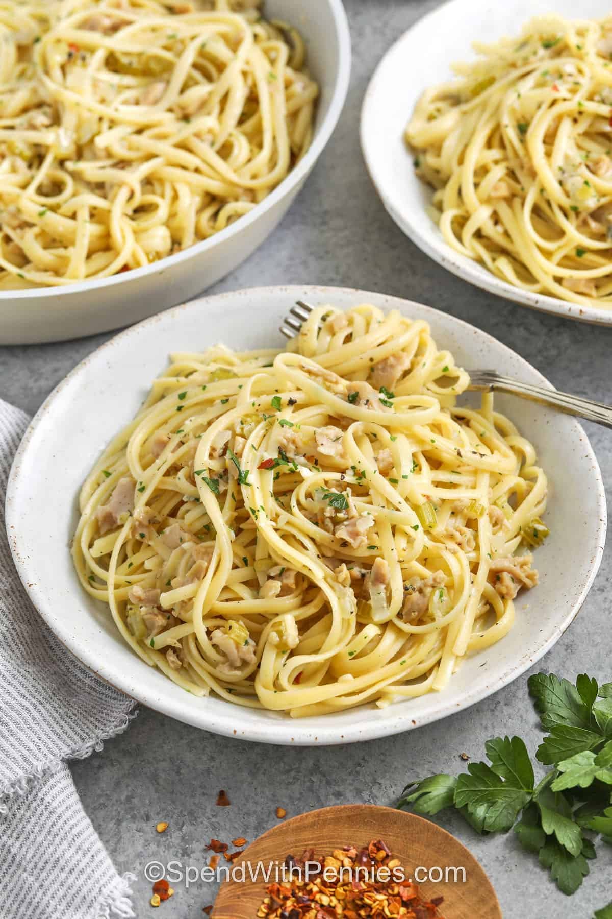 Linguine with clam sauce makes an easy pasta recipe with fresh and bold flavors. Garlic, celery, and onion simmer in white wine and clam juice before butter and lemon zest finish the sauce. Tossed with linguine and sprinkled with parsley, this dish is the best way to make a seafood spaghetti that feels both comforting and gourmet. Simple pantry ingredients turn into a bright, fresh pasta dinner everyone will rave about at the table. #spendwithpennies plated Linguine with Clam Sauce with a fork