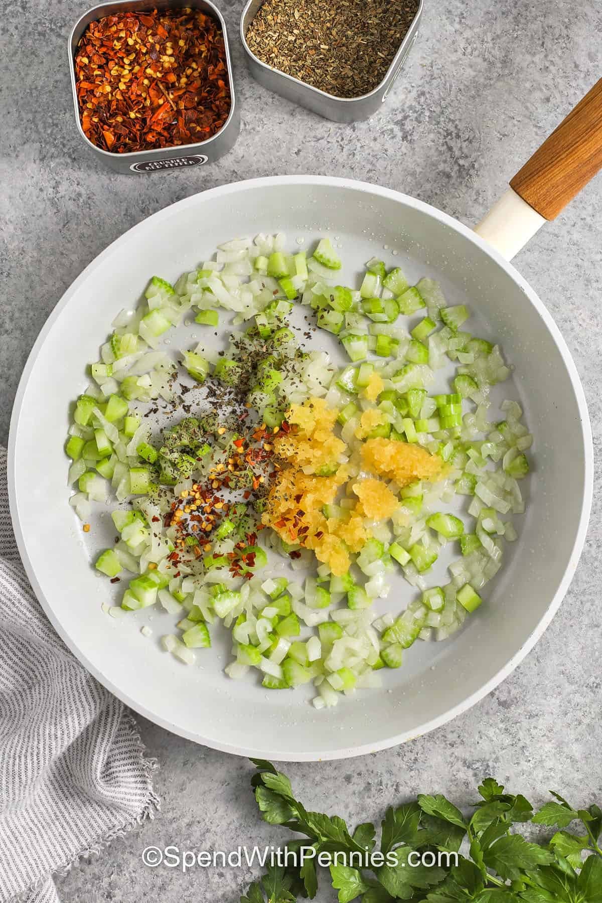 Linguine with clam sauce delivers the taste of the sea with fresh, simple ingredients. Garlic, celery, and onion form a flavorful base for clams in a white wine sauce finished with butter and lemon zest. Tossed with linguine and sprinkled with parsley, this recipe makes a satisfying and elegant pasta dinner at home. Ideal for spaghetti lovers who want a comforting seafood twist with a touch of sophistication. #spendwithpennies adding ingredients to pan to make Linguine with Clam Sauce