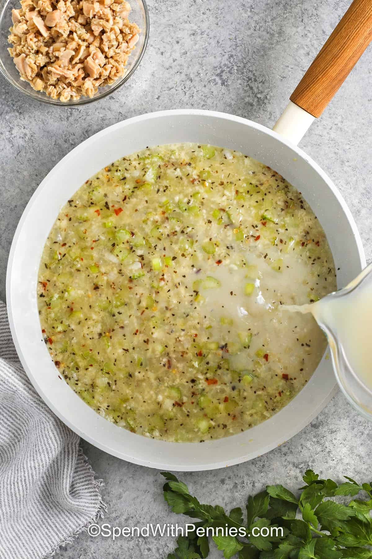 Linguine with clam sauce brings the taste of the sea to your pasta pot with fresh flavors and simple ingredients. Garlic, celery, and onion create a base for clams in a white wine sauce, finished with butter and lemon zest. Tossed with cooked linguine and sprinkled with parsley, this recipe is one of the best ways to make an elegant pasta dinner at home. Perfect for spaghetti lovers seeking a fresh seafood twist that feels both comforting and gourmet. #spendwithpennies adding liquids to pan to make Linguine with Clam Sauce