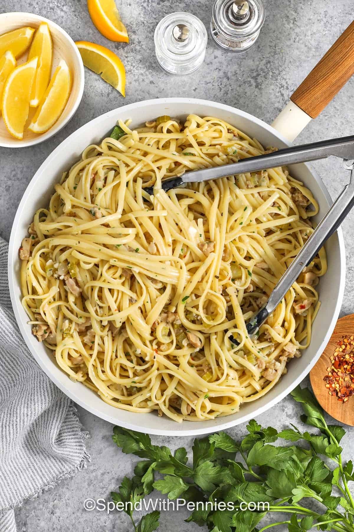 Linguine with clam sauce turns pantry staples into a fresh, flavorful pasta dinner with tender clams, garlic, celery, and onion in a bright white wine sauce. Finished with butter, lemon zest, and parsley, this recipe coats every linguine strand with savory goodness. Perfect for spaghetti nights or any dinner you want to feel special, it’s one of the best ways to make a simple can of clams taste fresh, bold, and restaurant-worthy. #spendwithpennies taking Linguine with Clam Sauce out of the pan