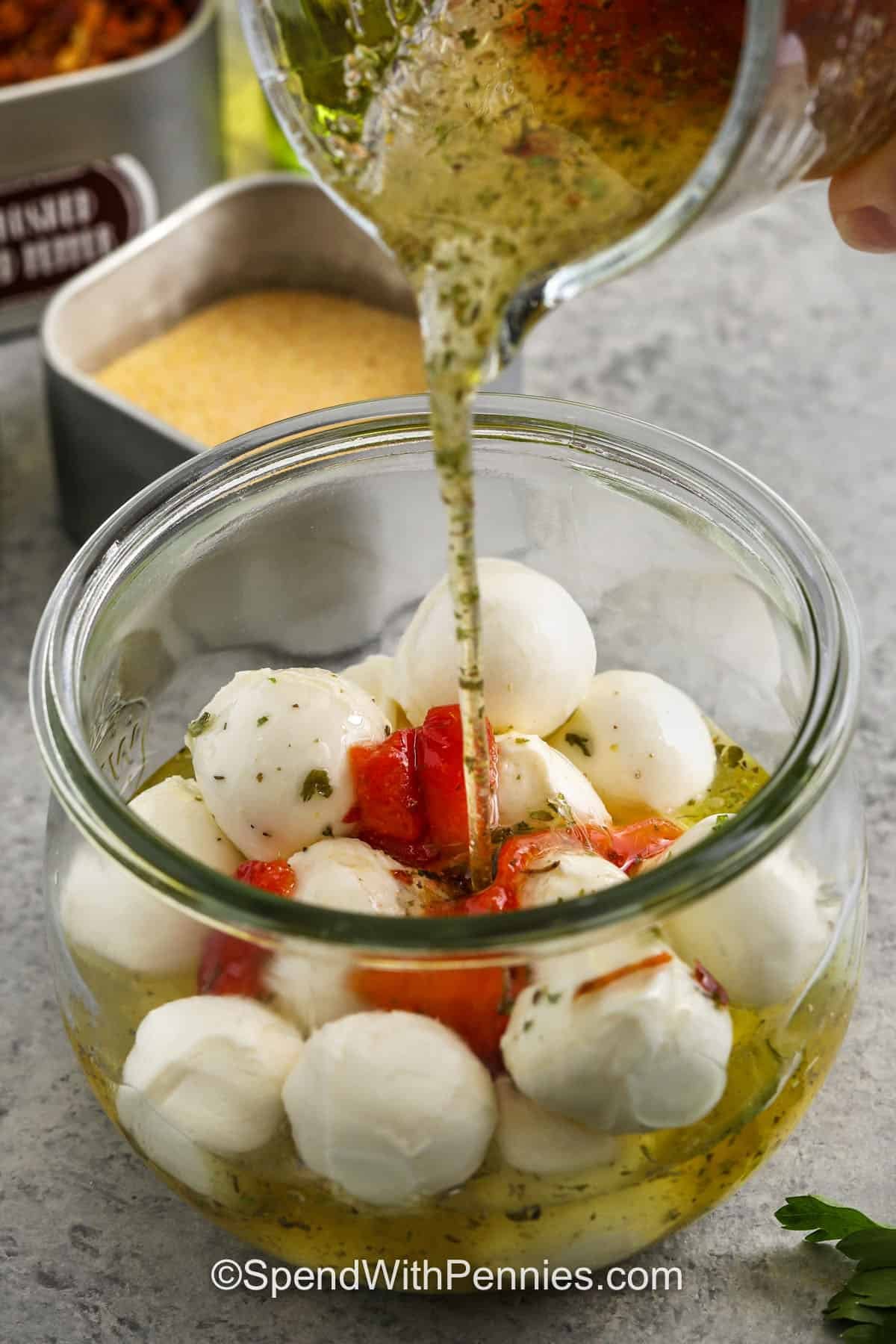 pouring the marinade into a jar of marinated mozzarella balls