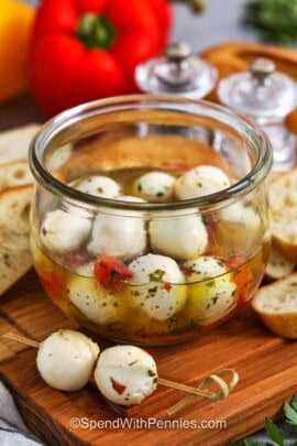 skewer with marinated mozzarella balls and jar and ingredients in the background