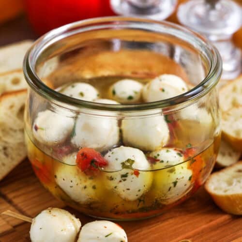 skewer with marinated mozzarella balls and jar and ingredients in the background