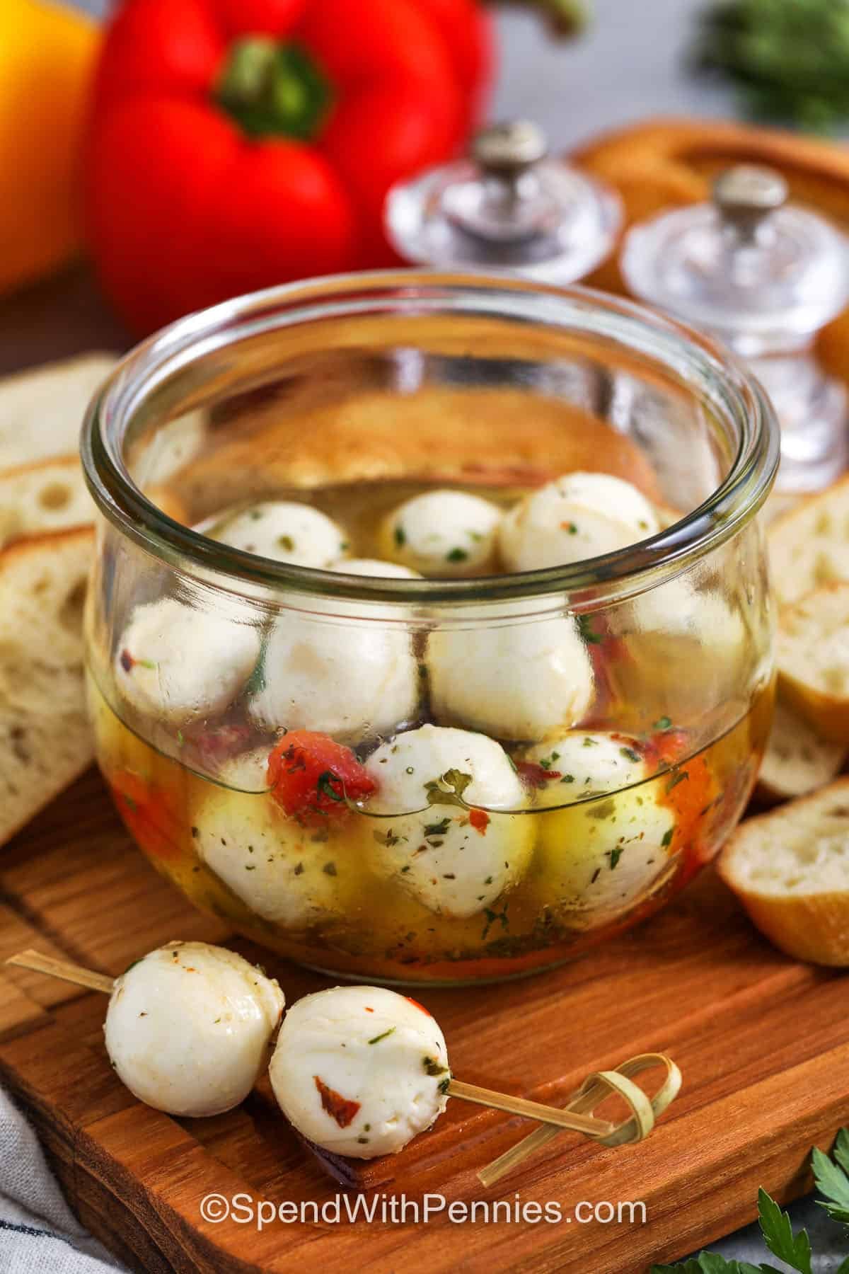 skewer with marinated mozzarella balls and jar and ingredients in the background