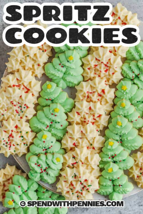 These classic spritz cookies are made with a buttery dough sweetened with powdered sugar and flavored with almond extract. They press cleanly into beautiful shapes and bake in just minutes, making them perfect for holiday trays or gifting. This easy recipe uses simple ingredients and requires no chilling. They will be ready for decorating in no time! #spendwithpennies Spritz Cookies on a plate with a title