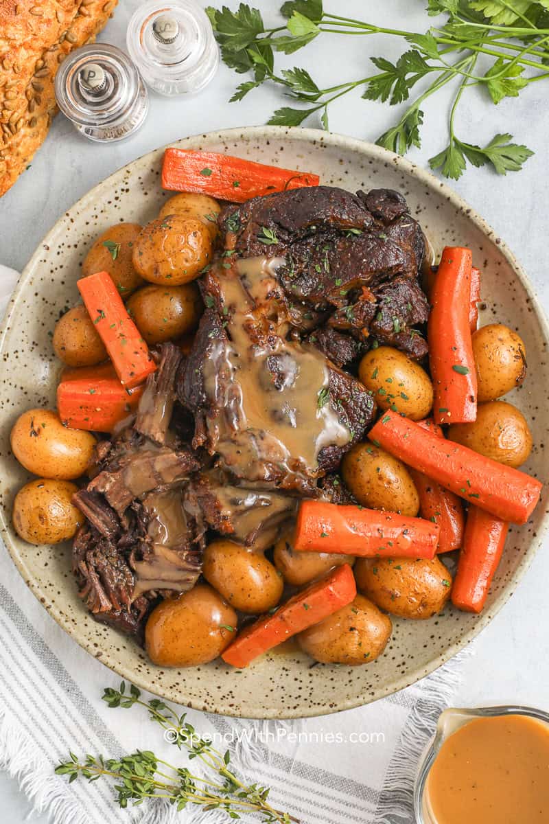 a cooked pot roast recipe with carrots and potatoes on a plate with gravy