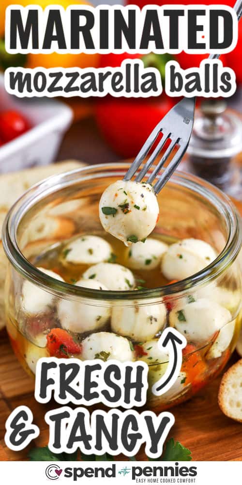 closeup of marinated mozzarella balls with a fork taking one out and writing