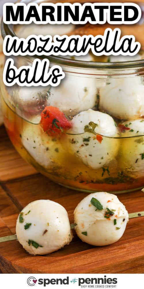 closeup of two marinated mozzarella balls on a skewer with jar in the background, and writing