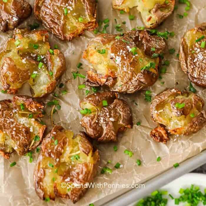 Roasted smashed potatoes on a baking sheet with chives
