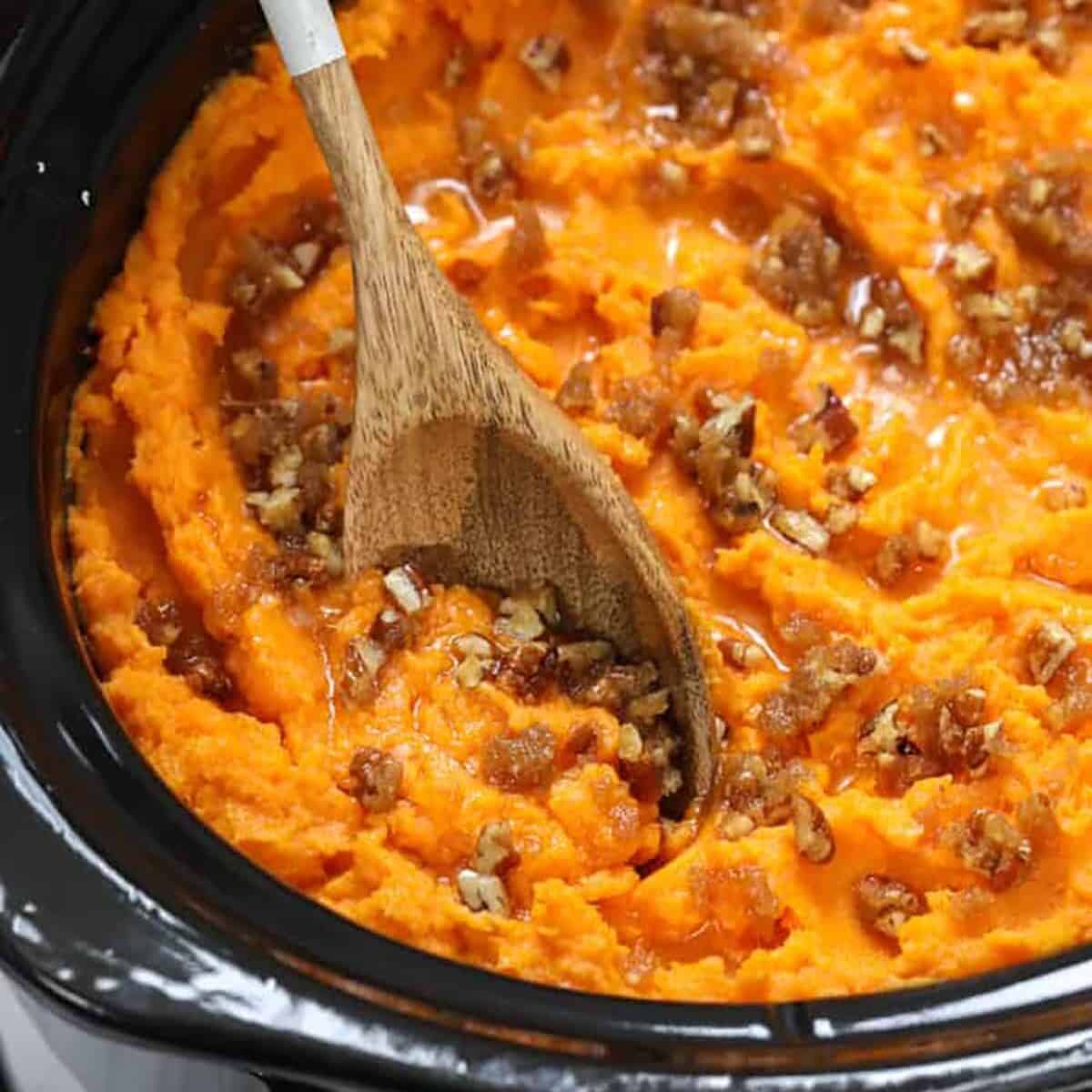 Crockpot sweet potato casserole in a crockpot with a wooden spoon