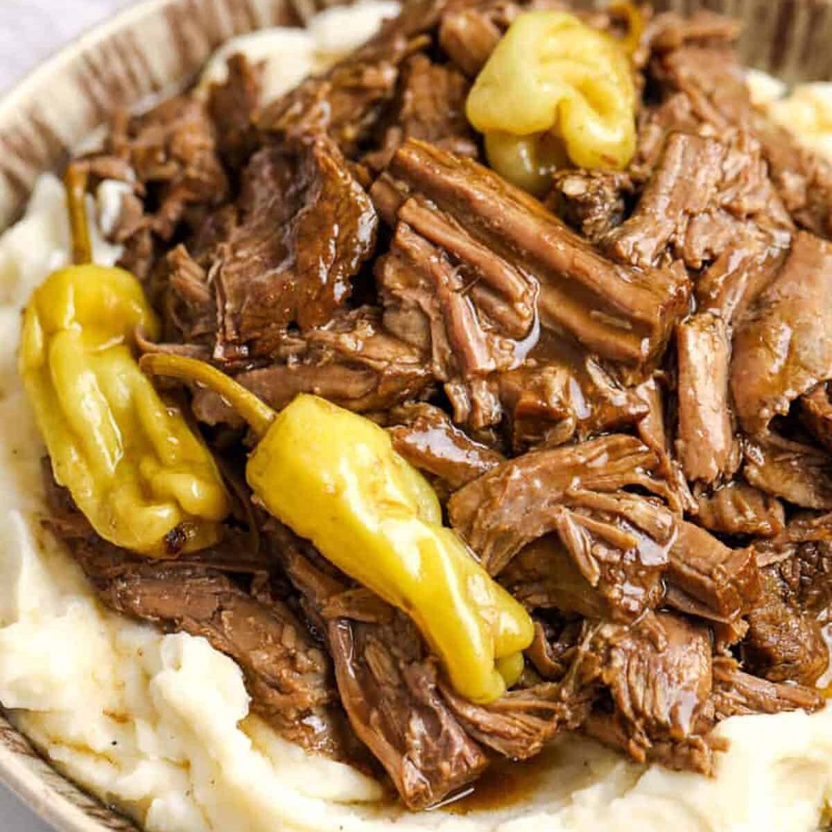 close up of Mississippi Pot Roast with jalapenos and gravy over potatoes