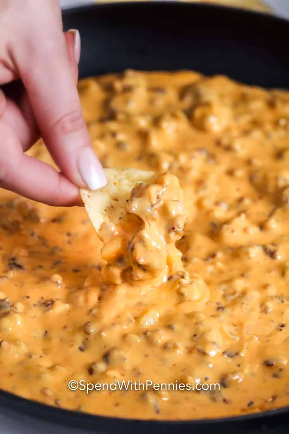 dipping a chip in Sausage Cheese Dip