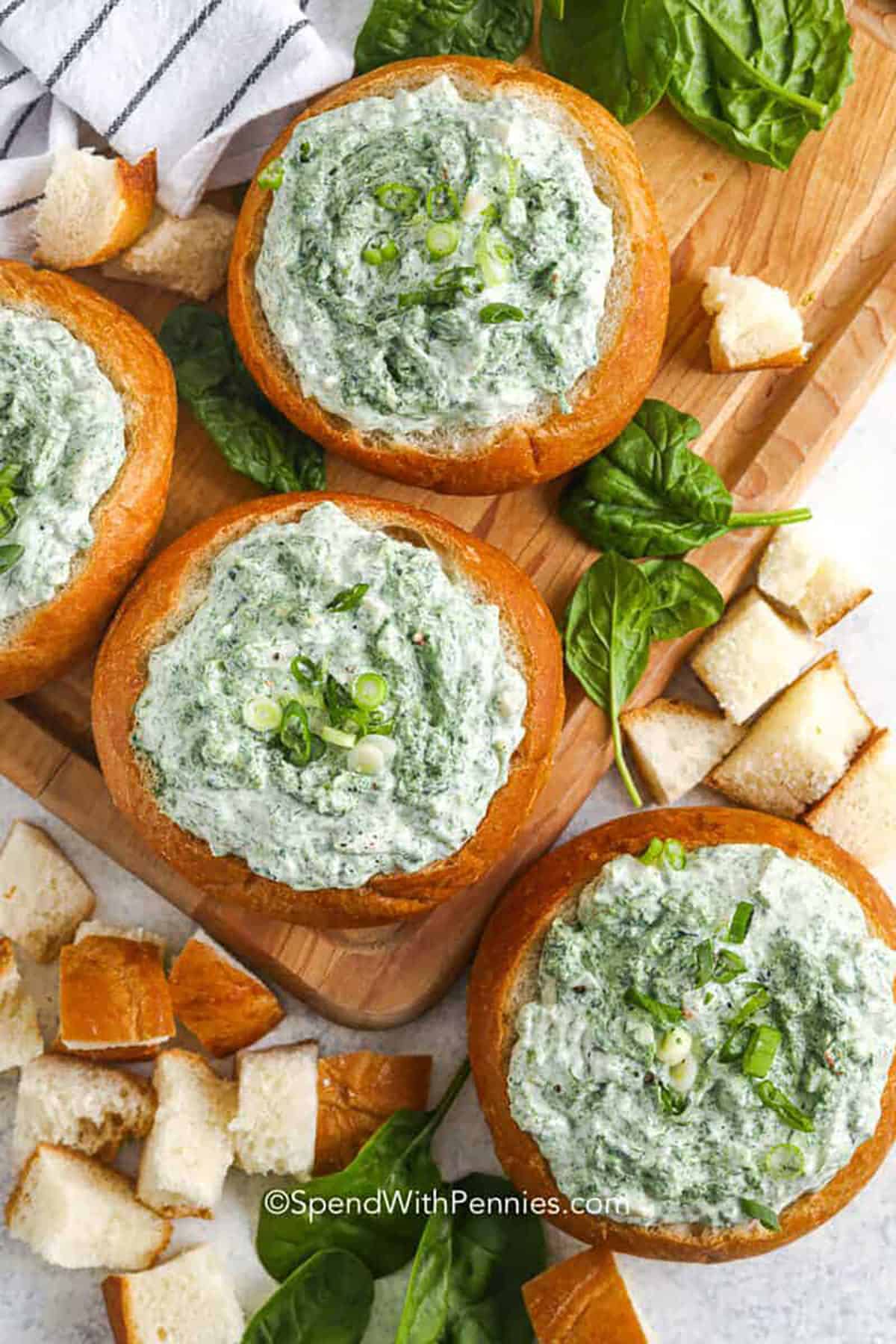 This spinach dip recipe is a creamy, cold classic with savory vegetable soup mix seasoning and crunchy water chestnuts. Thaw frozen chopped spinach and squeeze it very dry so the dip stays thick and scoopable. Stir with sour cream, mayonnaise, and chopped green onions, then chill to let the flavor blend. Serve with crackers, crostini, tortilla chips, or a colorful veggie tray. #spendwithpennies Spinach Dip in bread bowls