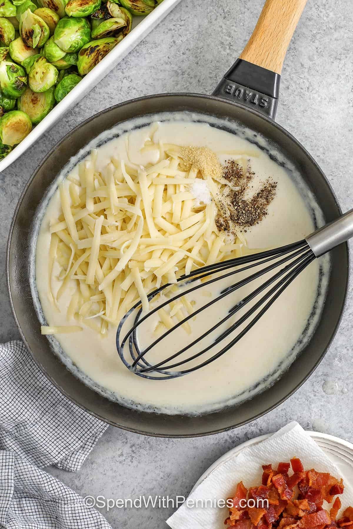 Serve a warm holiday side with this creamy Brussel sprout casserole. Tender sprouts are covered in smooth cheese sauce and topped with smoky bacon and a buttery finish. It pairs wonderfully with classic Christmas dishes and can be made ahead for convenience. The rich, comforting flavors make it a hit for any winter gathering. #spendwithpennies adding cheese and seasonings to roux to make Brussels Sprout Casserole