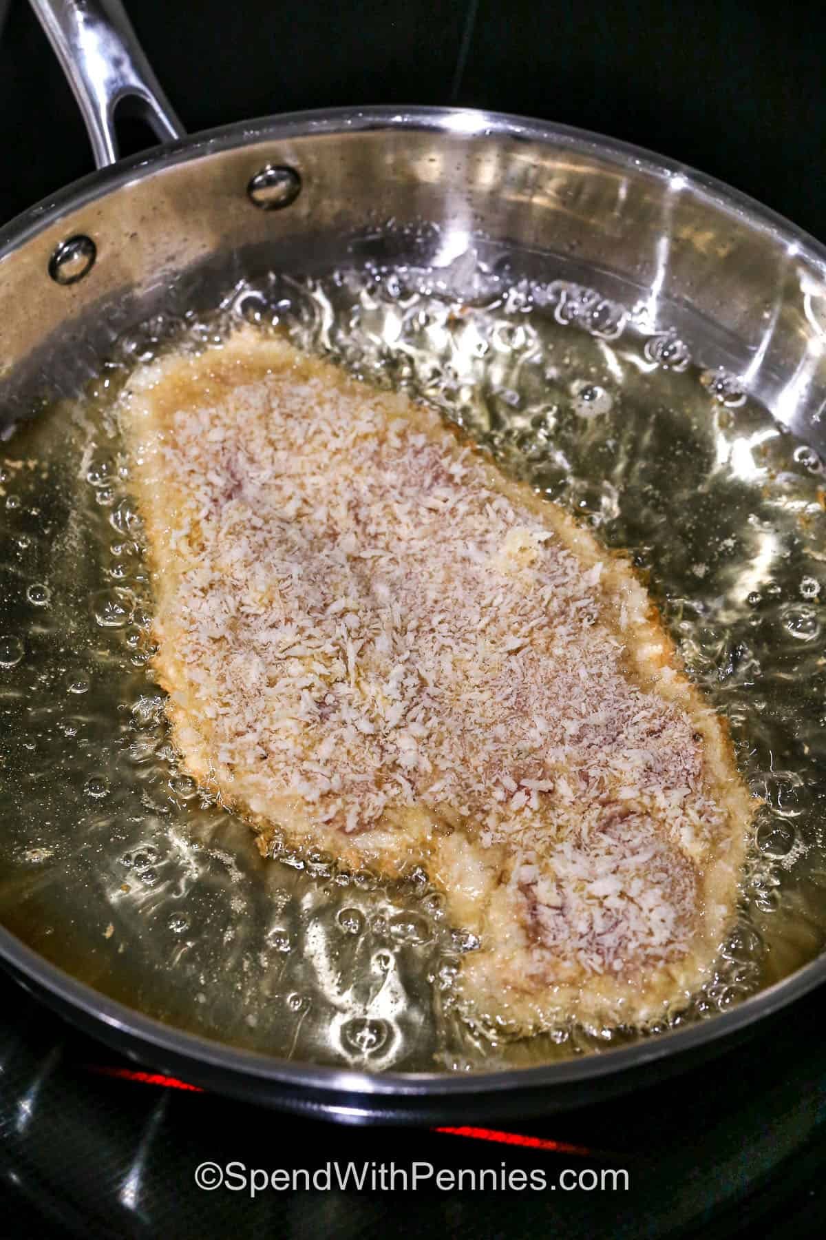 adding chicken to hot oil in pan to make Chicken Katsu