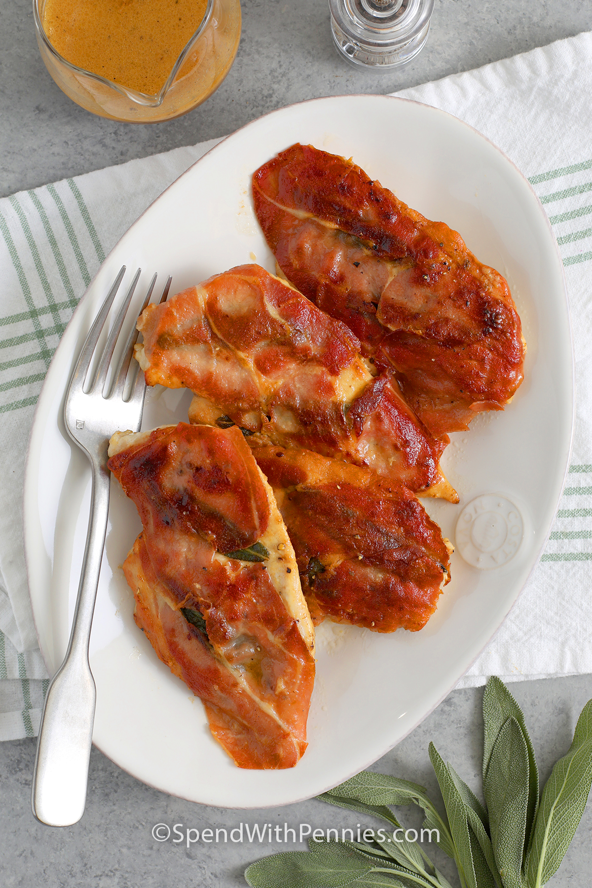 Serving plate with chicken saltimbocca and a fork with butter and white wine sauce off to the side
