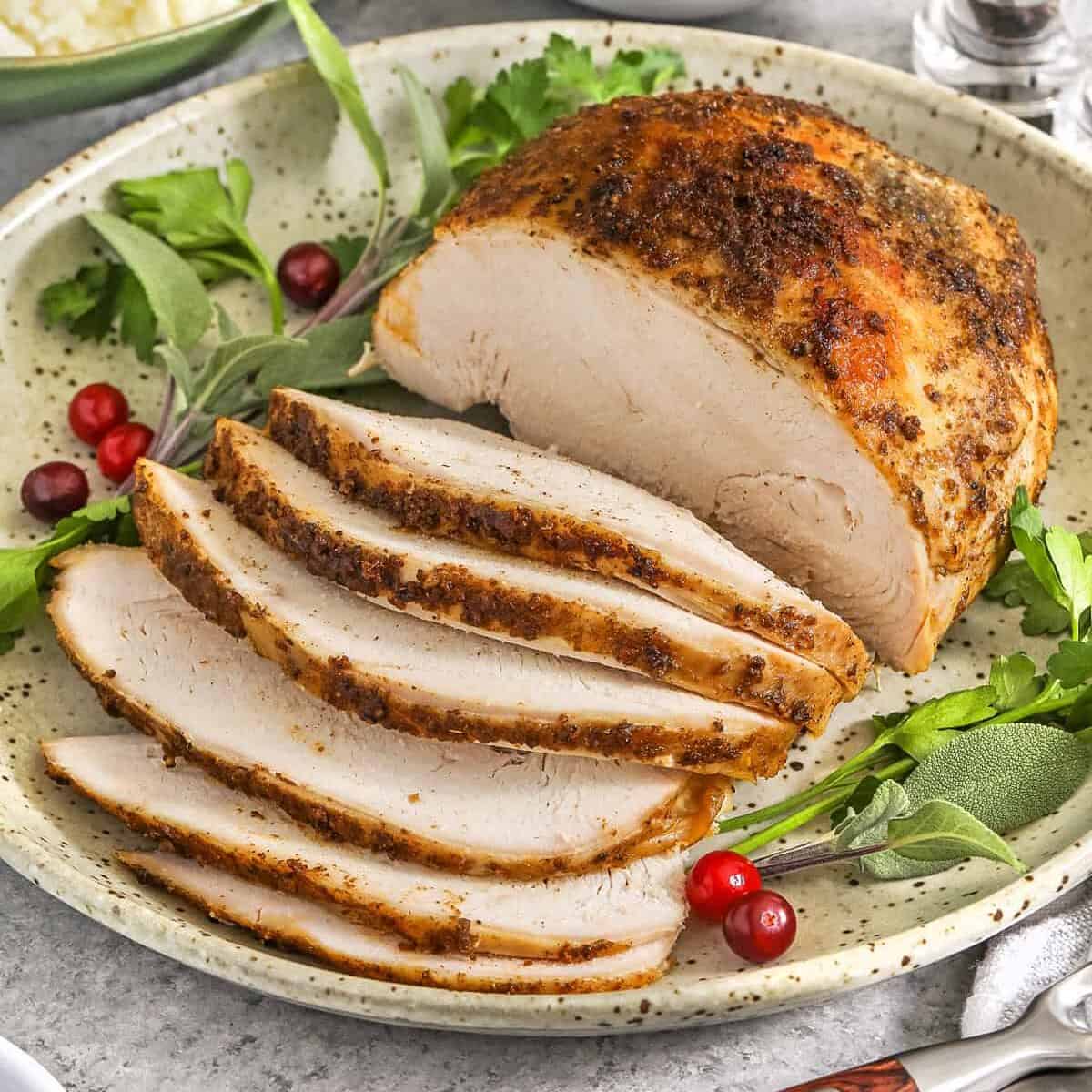 turkey breast on a plate with garnish for Crockpot Turkey Breast