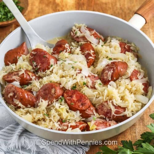Kielbasa and Sauerkraut in a pan with a spoon