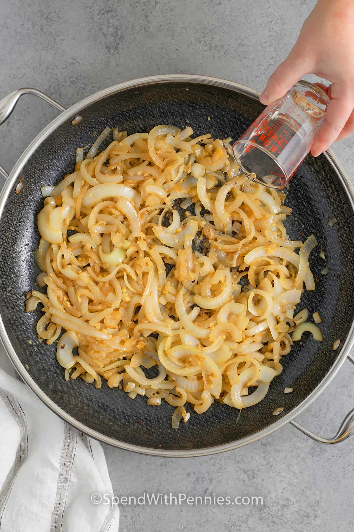 Adding white wine to a skillet of caramelized onions and garlic.