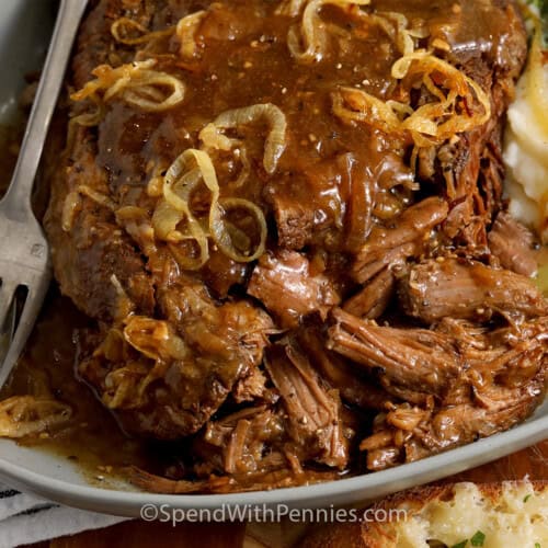 Close up of French Onion Pot Roast on a platter with mashed potatoes and cheese toasts.