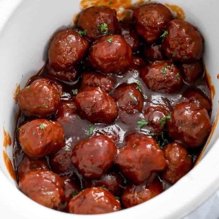 Grape jelly meatballs in a crockpot garnished with parsley