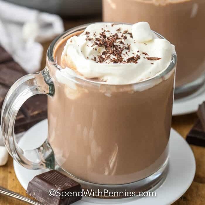 Homemade hot chocolate in clear mugs with whipped cream and marshmallows