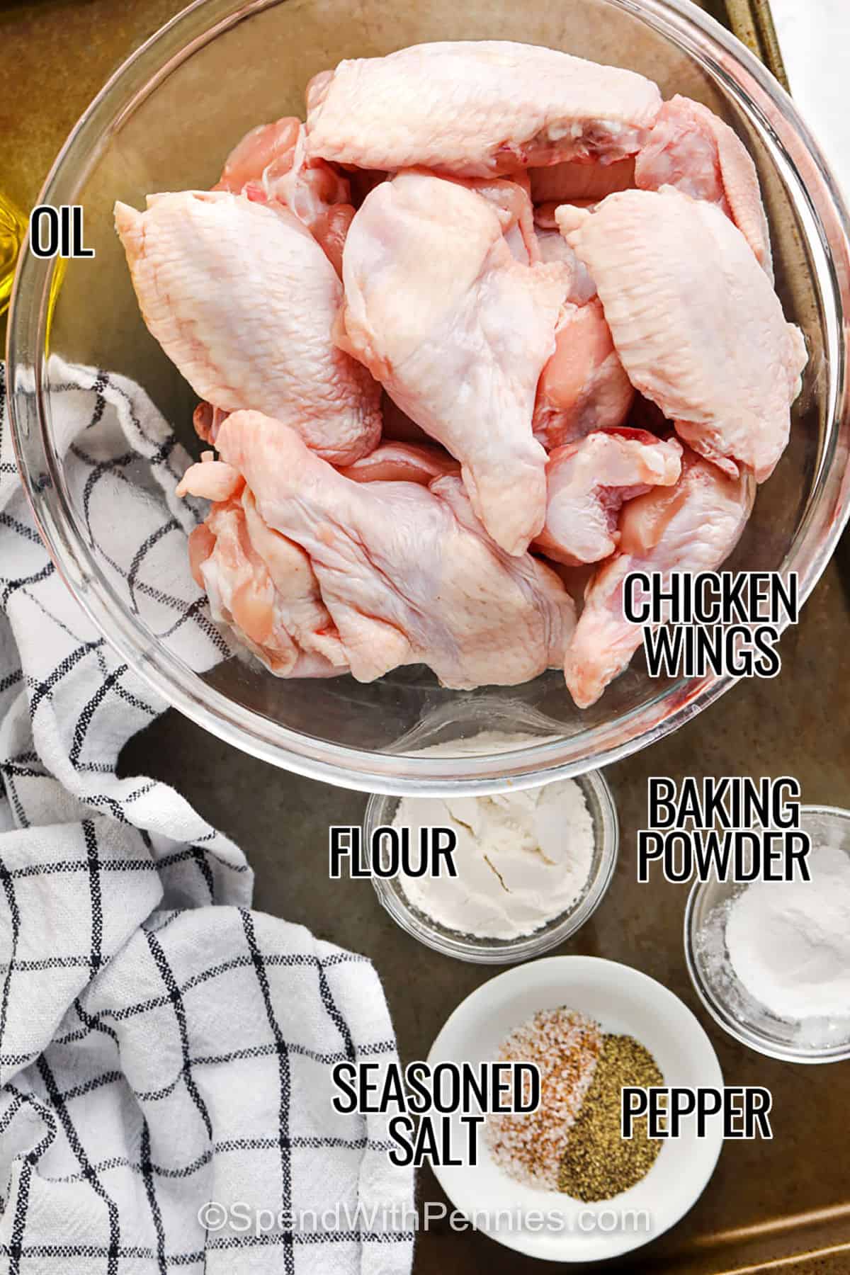 These crispy baked chicken wings are juicy inside with golden, crackly skin on the outside. The secret is patting the wings very dry, coating with flour and baking powder, then chilling uncovered so the skin dries out. Bake them on a rack so hot air circulates all around, then finish with a quick broil if you want even more crunch. Serve them dry with ranch dressing or toss them in buffalo sauce right before serving. #spendwithpennies oil , chicken wings , baking powder , flour , seasoned salt and pepper with labels to make Actually Crispy Oven Baked Wings